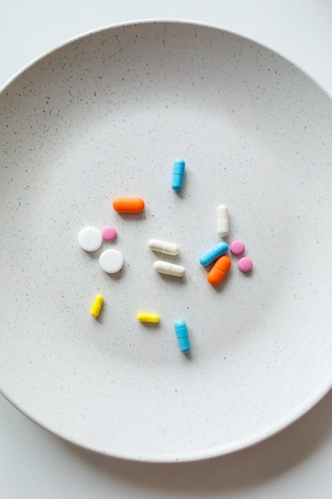 Assorted colorful medication capsules and tablets displayed on a white plate.